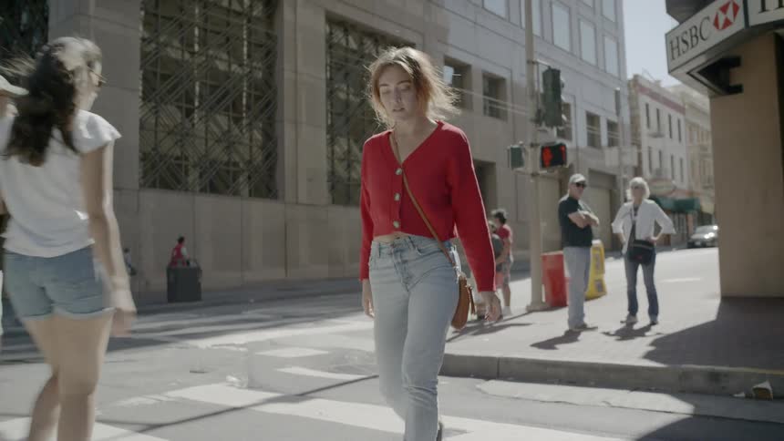 Woman wearing a red sweater and high hills goes past the pedestrian crossing in the city