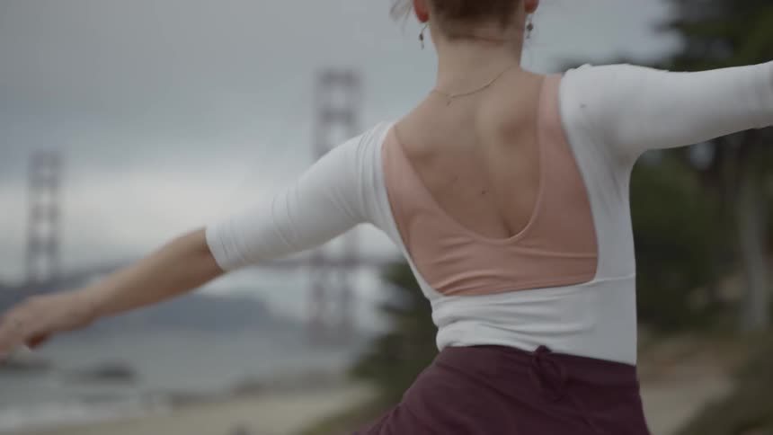A woman dancing on the beach near the golden gate bridge