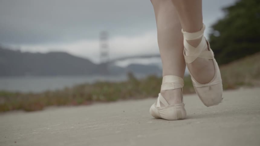 Ballerinas feet move rhythmically following a set sequence of steps on the hill by the seaside with the long distance view of golden gate bridge dance