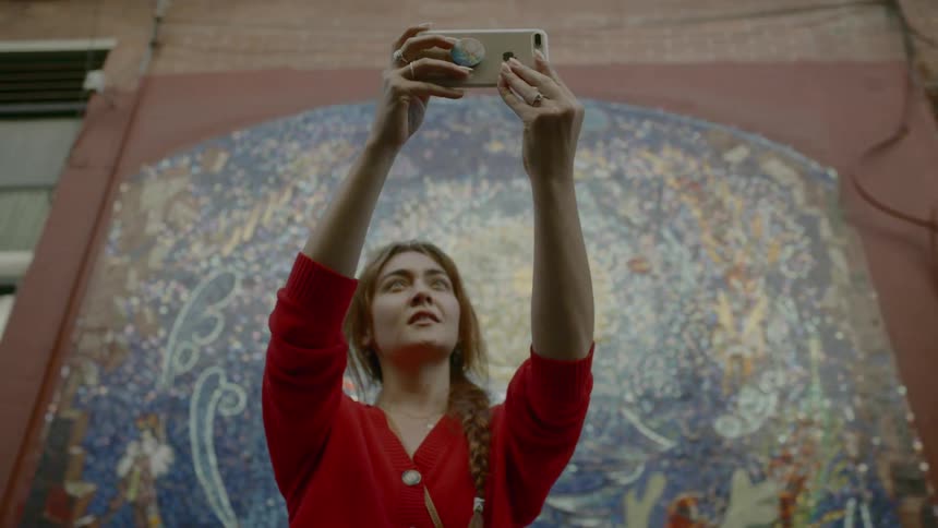 Woman taking a selfie against a painted wall on a cell phone