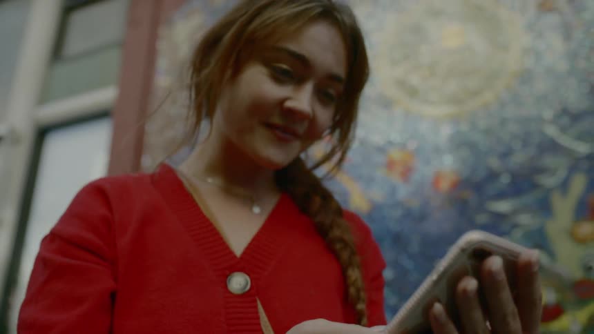 A woman smiles as she looks down and taps on her phone