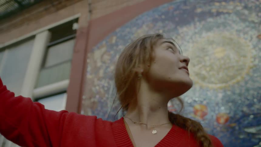 A woman takes a selfie in front of a mural painted on a building
