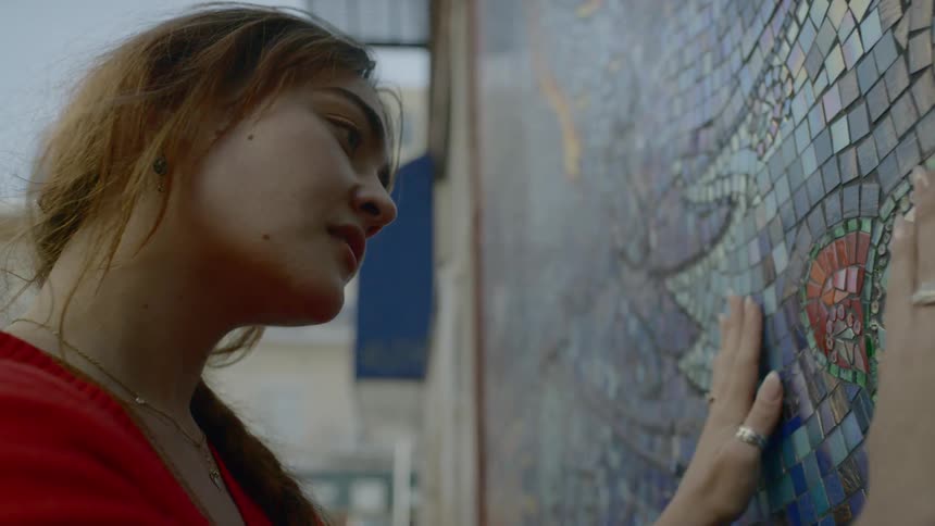 A woman is touching the artwork on the wall