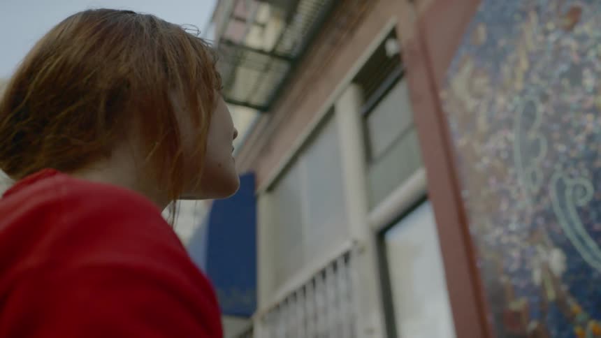 A woman standing outside taking a picture of a mural with her smart phone