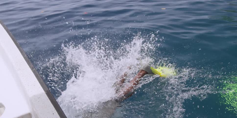 A man leans back on a boat diving underwater
