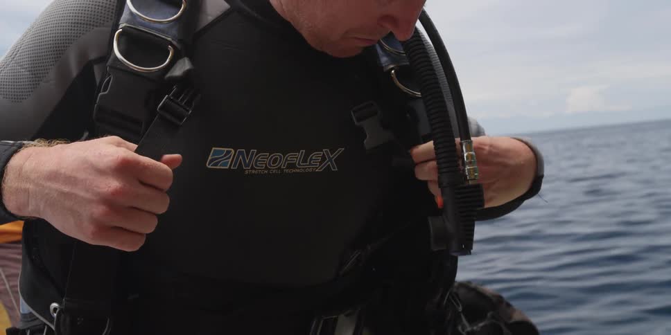 A diver straps equipment to his back