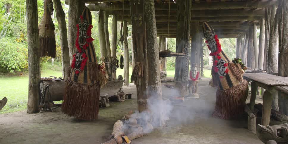 People in native costumes dance near a smoldering fire