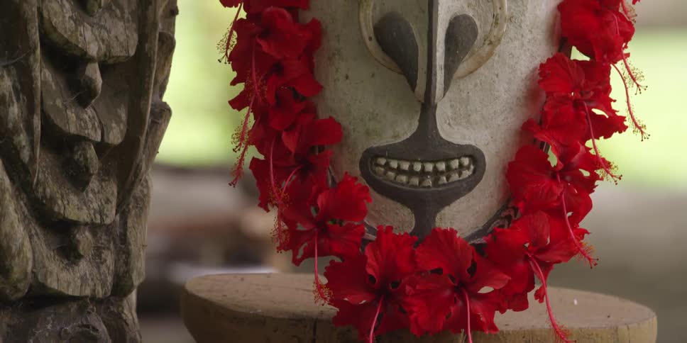 A mask covered covered in flowers is sitting on a stool