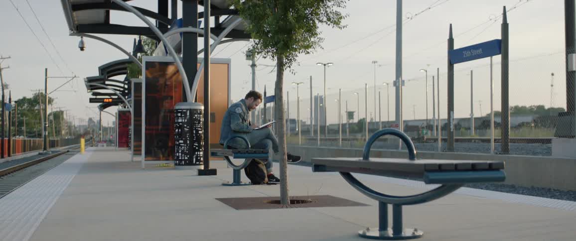 Man sitting in the bench on the train station uses a tablet