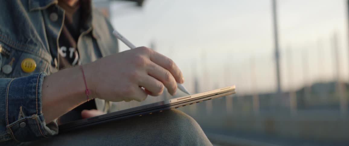 Man sittin on the bench uses tablet with a stylus at the railway station