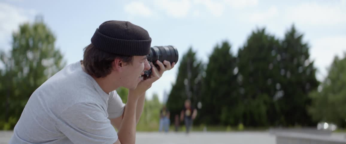 A photographer holds up his camera and takes a picture at a skate park