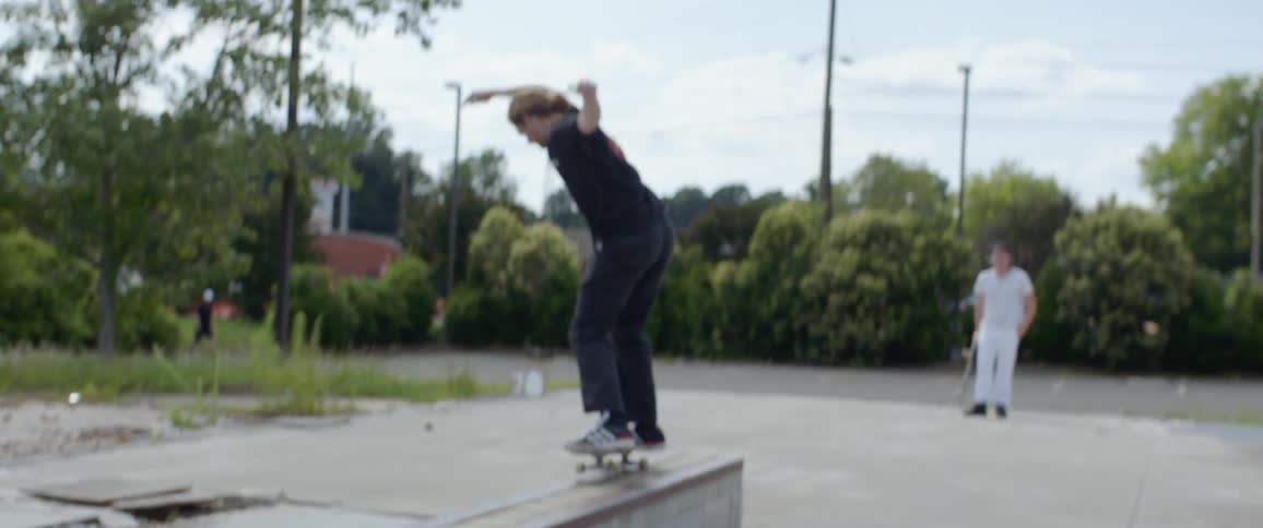 A skateboarder jumps a concrete barrier and falls off