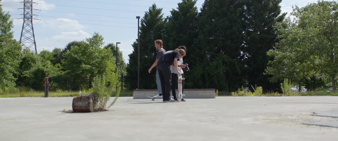 A skateboarder rides past a man and photographer looking at the camera