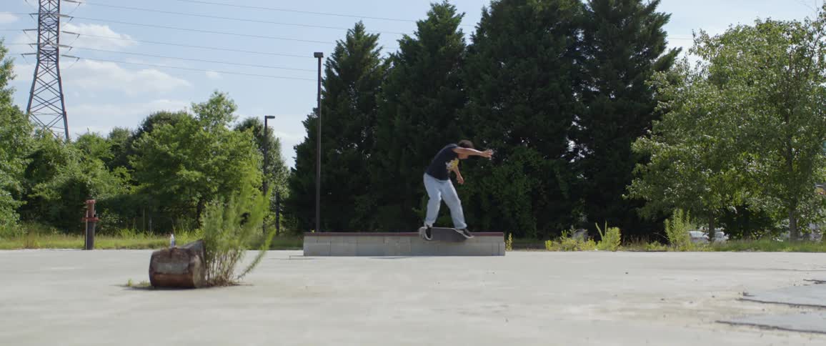 A teenager jumps on a bench with his skateboard