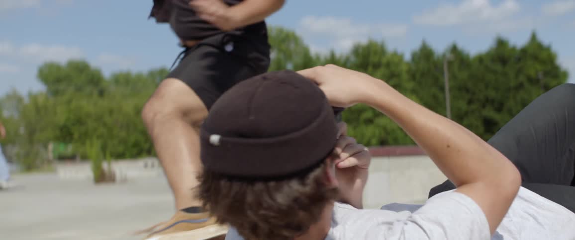 A young man lies down to photograph a skateboarder