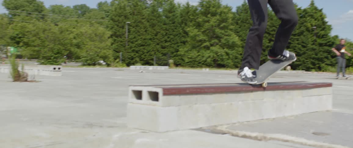 A young man attempts to perform a trick on his skateboard but fails to nail the landing as a friend snaps photos nearby
