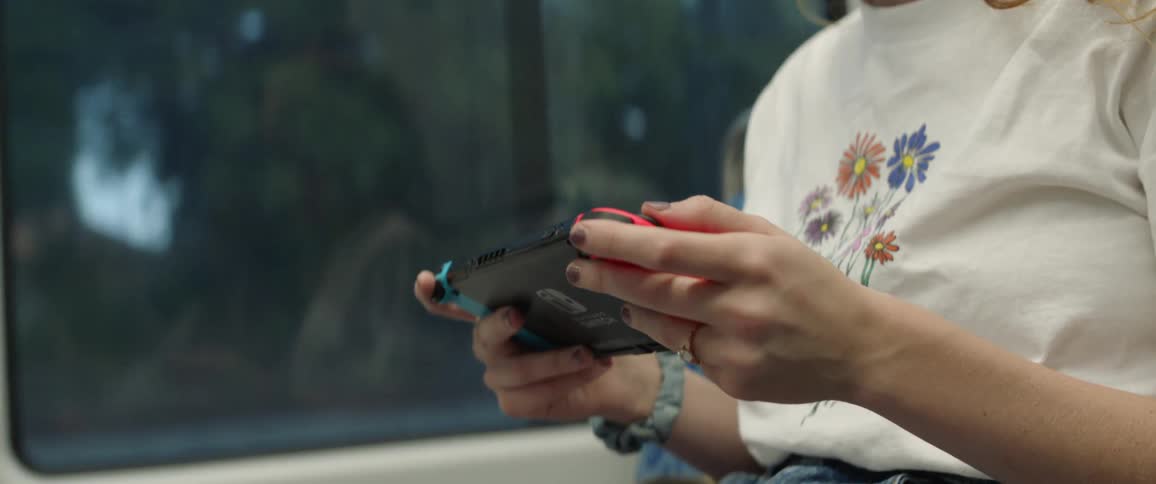 A woman sitting on a bus playing nintendo switch