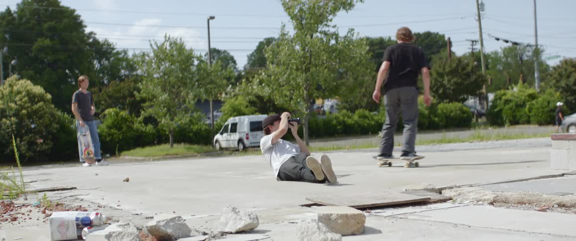 Teenager photographing skateboarder as he makes a jump