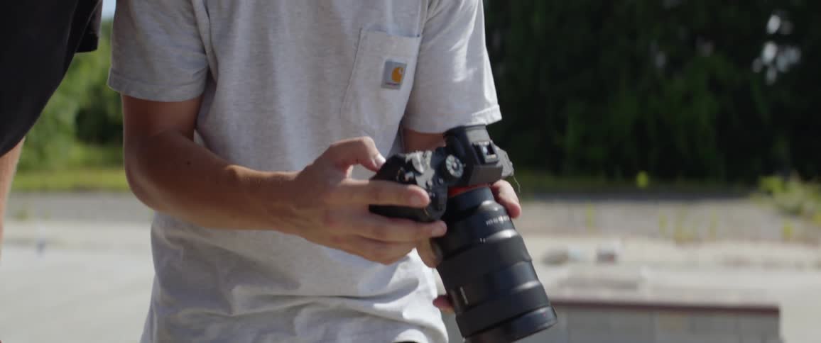 Male photographer and skateboarder check out the photographs which was taken by the photographer outdoors