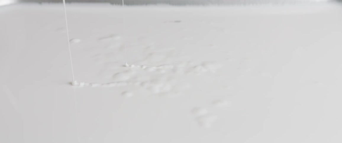 A thick white liquid that resembles paint drips from above where it is collecting below