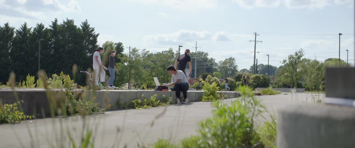 A group of boys ride skateboards outside