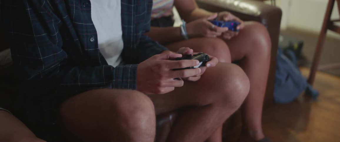 A man and woman sit on a couch and play a video game