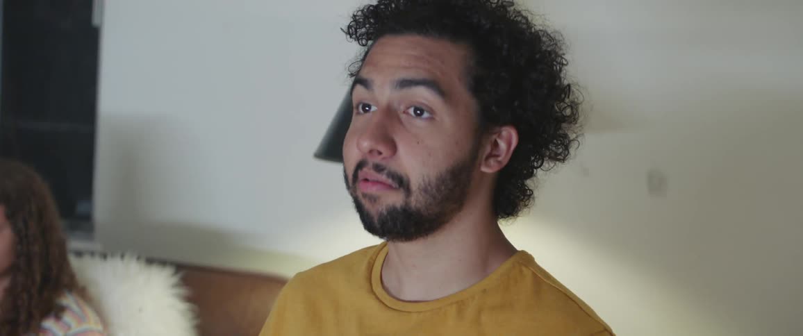 A man is surprised and amused while watching something in a living room