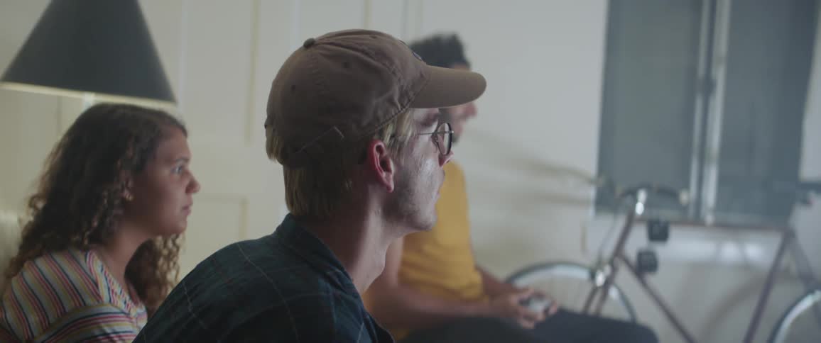 Friends sit in living room playing video games