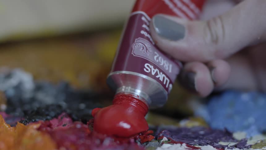 A person squeezing paint from a tube