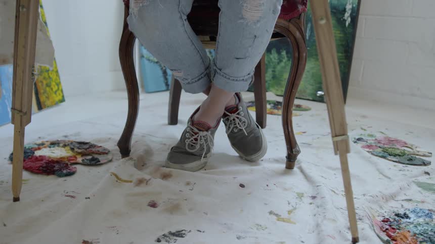 Artist palettes on drop cloth under easel and artist