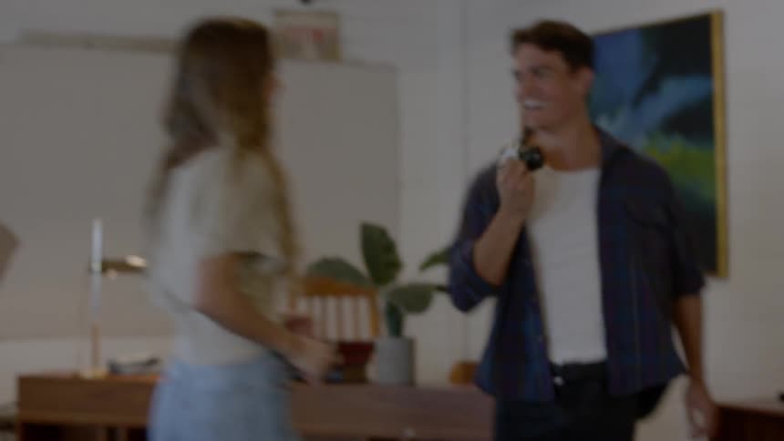 A young man playfully plays keep away with a camera and his female companion