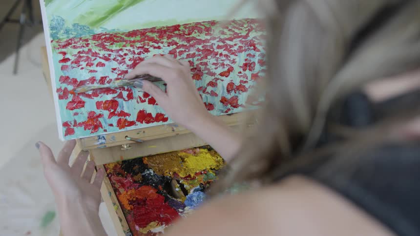 A woman painting on a canvas with a utensil