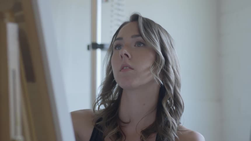 Female artist paints a picture in a room