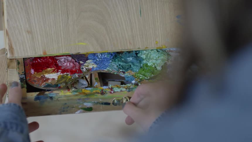 A woman opening a drawer with a wooden paint palette inside