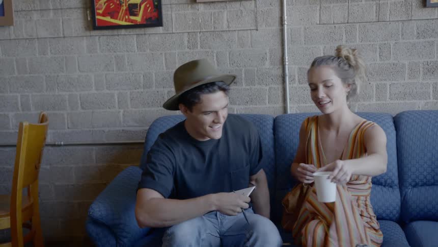A man and a woman sit down on a blue couch at the same time