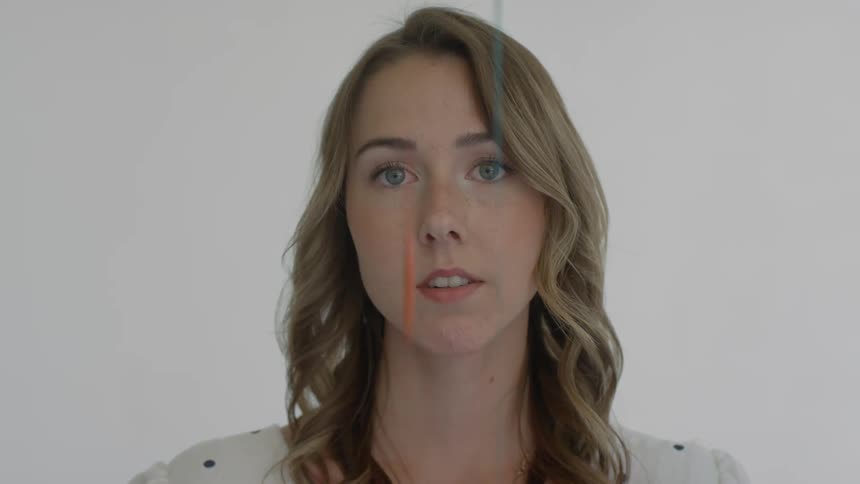 A woman stares directly at the camera as various colors of paint drip in front of her face