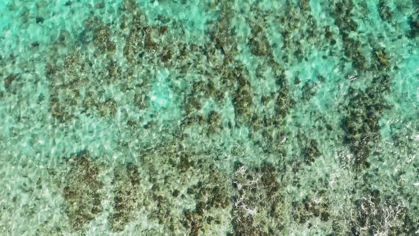Turquoise ocean water is so clear that rocks are visible under the surface