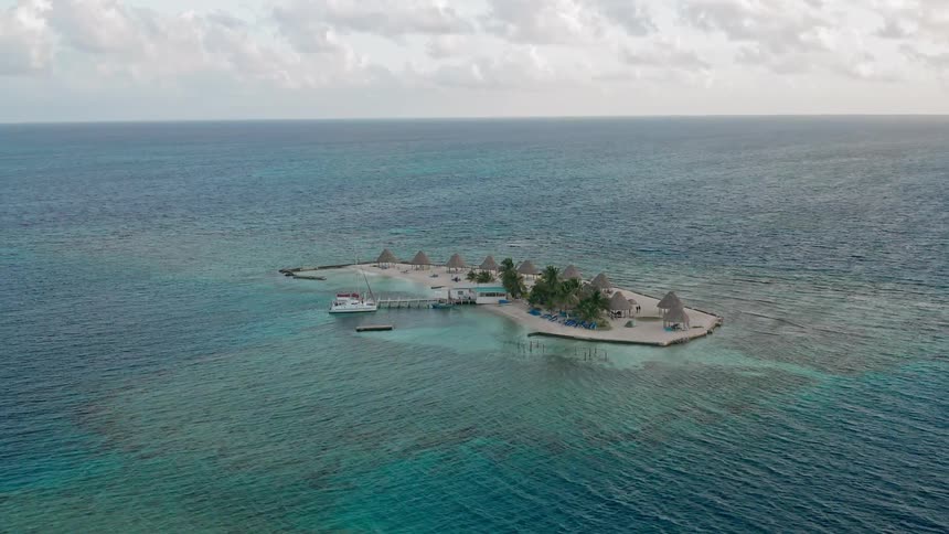A boat is docked at a tiny tropical beach island
