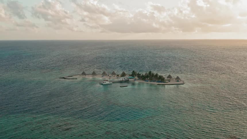 A small island sits alone in the vast blue ocean