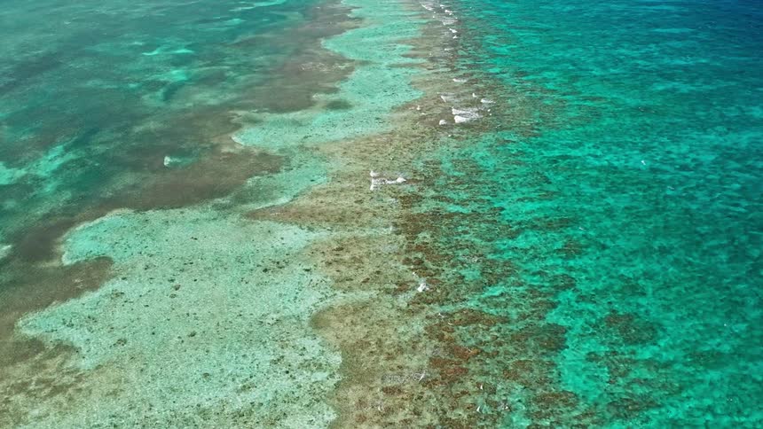 Waves crashing across a sandbar in the middle of tropical waters