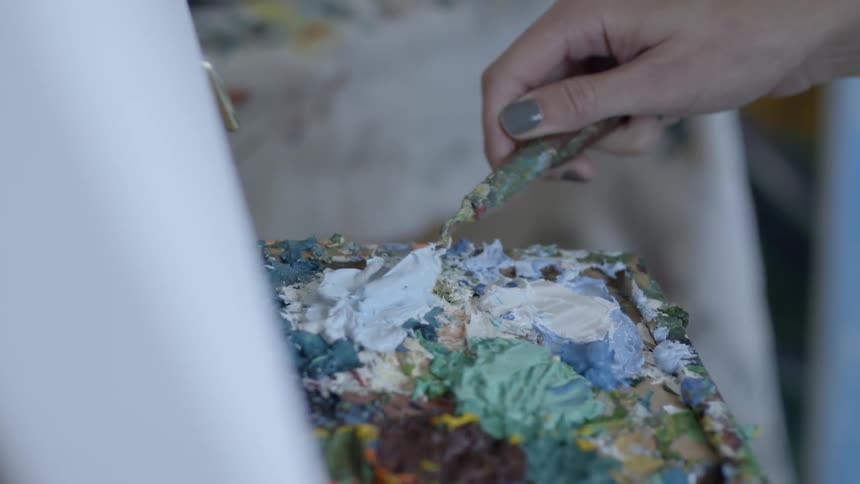 A woman uses a tool to scoop paint from a tray