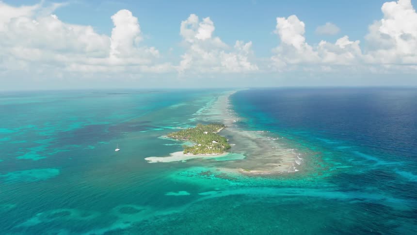 A small island sits alone in the vast blue ocean
