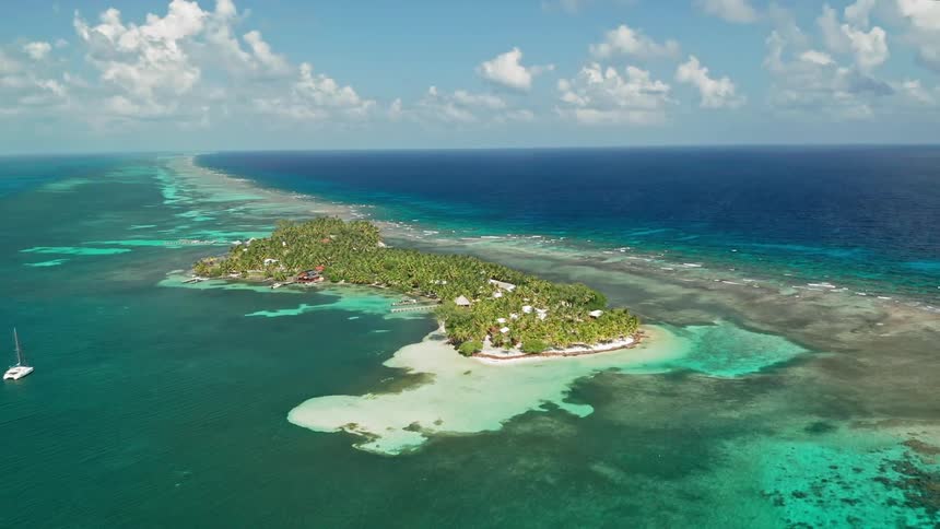 A boat floats in the water by an island