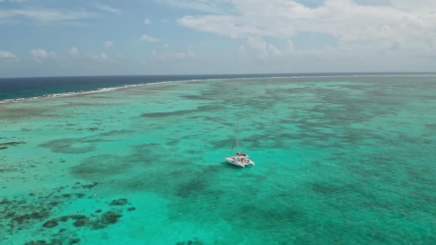 Boat floats on the blue ocean water under a blue sky