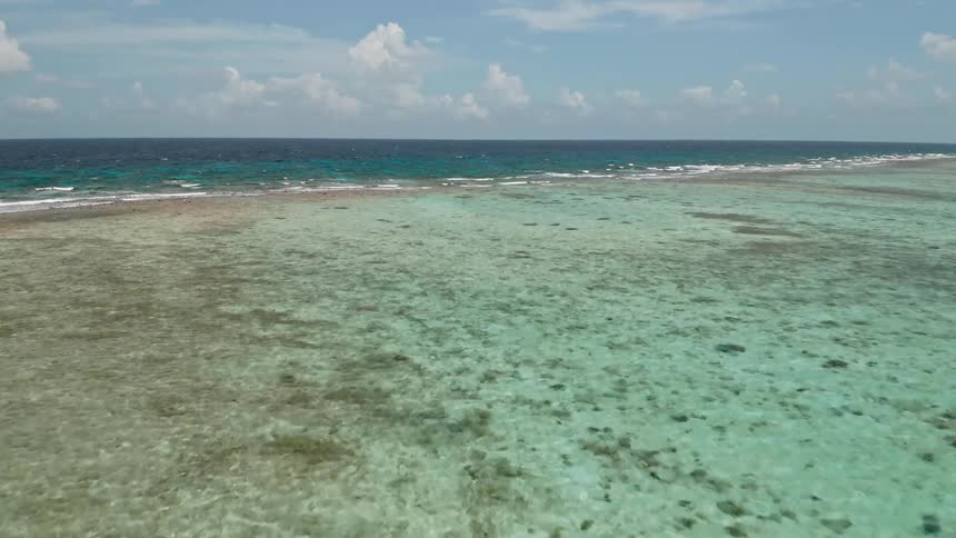 Waves breaking across the coast with shallow clear water