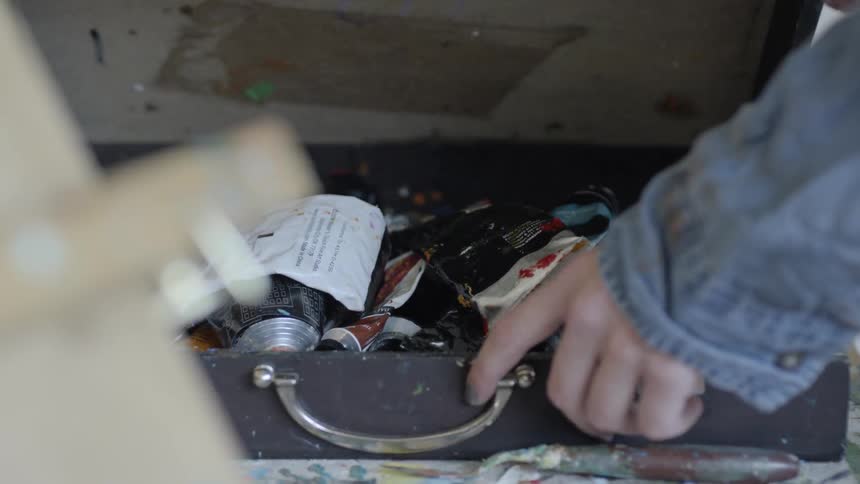 A person opens a briefcase style box with a bunch of random items inside