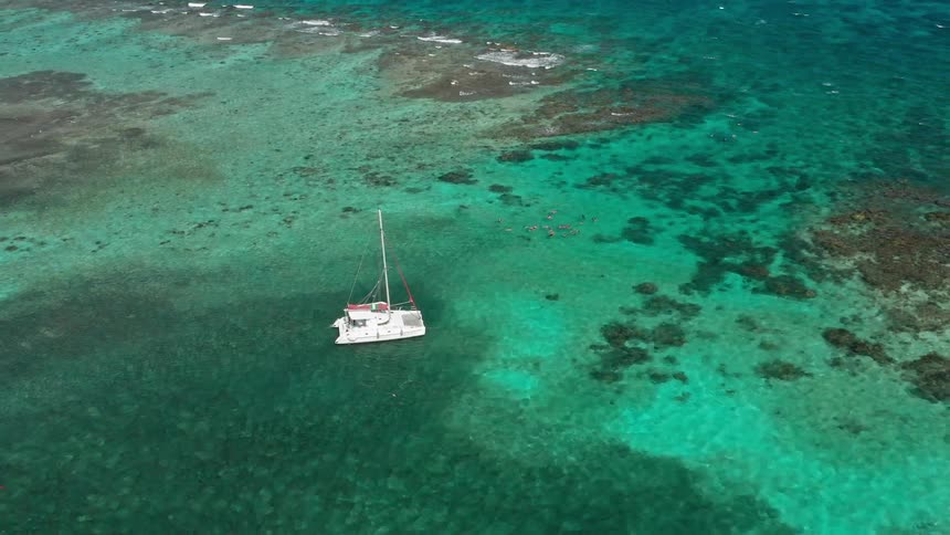 A yacht in the beach next to rocks
