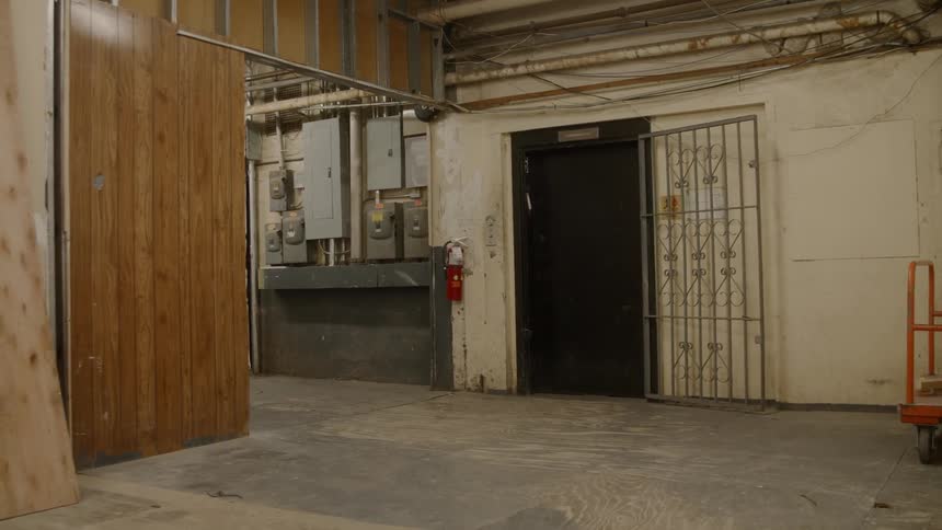 Several breaker boxes hang on a wall beside a black doorway