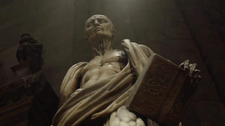A statue on a man holding a book in a museum