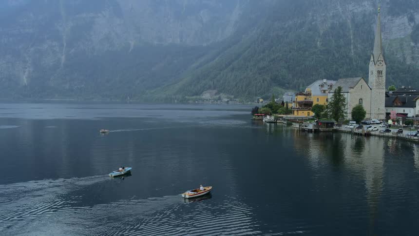 A village next to a lake with boats and mountains in the background